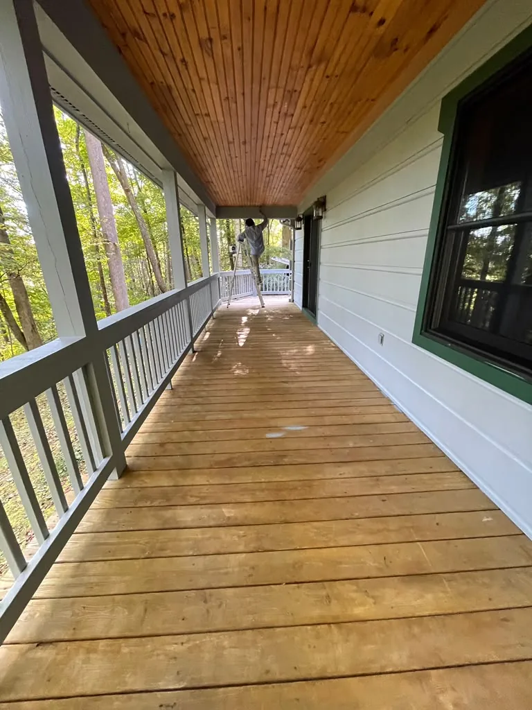 Finished covered porch with stained wood floor and white siding