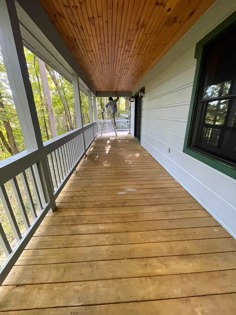 Painting work taking place on a covered wooden porch at a mountain home