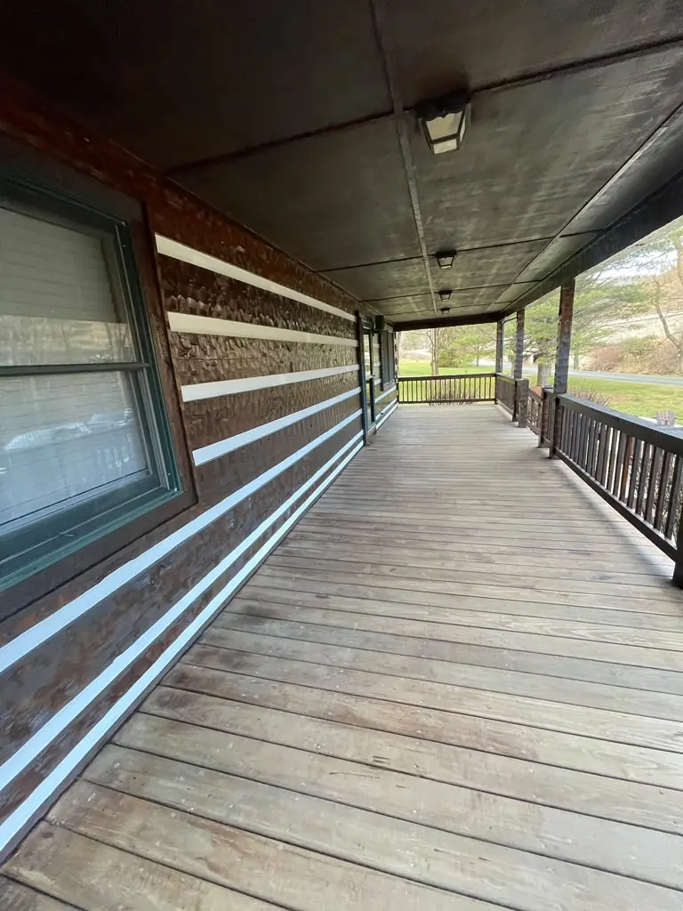 Wide view of weathered wooden porch decking and contrasting exterior siding